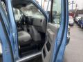 A blue 2009 Ford Econoline with the front door open showing a gray interior including the steering wheel and dashboard