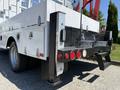 White 2013 Ford F-550 with a utility body featuring a ladder rack and tool compartments visible at the rear including lights and a step for access