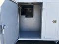 A 2005 Freightliner M2 106 with an open cargo compartment door revealing a metal interior with hooks and a small window