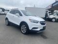 A white 2018 Buick Encore with a sleek design and alloy wheels parked in a lot showcasing its front profile and distinct grille