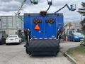 A blue 2013 International DuraStar 4300 street sweeper with reflective lights and a large broom attachment at the front
