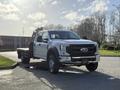 A 2020 Ford F-550 pickup truck with a flatbed, featuring a chrome front grille and large tires, positioned prominently in the foreground