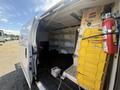 A 2017 Chevrolet Express van with an open side door showing its empty cargo area and yellow storage compartments along the wall
