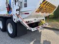 A 2011 Autocar Xpeditor garbage truck with a yellow caution sign on the back and a bucket hanging from the rear door