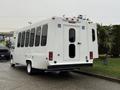 A white 2017 Ford E450 van with large windows and wheelchair accessibility signs on the rear doors