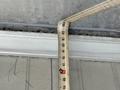 A measuring tape bent at a right angle showing measurements in inches and feet