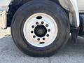Close-up of the large tire and wheel of a 2015 Ford F-750 with a white rim and patterned tread marking the tire brand and model