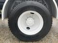 Close-up of a wheel and tire from a 2016 Freightliner 108SD featuring a white rim and heavy-duty tread design