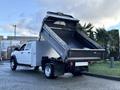 A white 2021 RAM 5500 dump truck with its bed raised, showing the interior of the bed designed for transporting materials