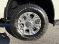 Close-up of a wheel from a 2023 RAM 3500 featuring a metallic silver rim with a prominent RAM logo and an all-terrain tire with visible tread patterns