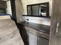 Interior view of a 2021 Jayco Jay Flight showing a dark wood countertop with multiple drawers and a mirror above it