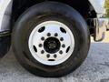 A close-up of a black tire with a white steel wheel featuring multiple black lug nuts