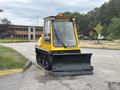 A yellow 2004 Bombardier SW48 with a front plow blade designed for snow removal standing on a paved surface