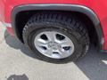 A close-up of a wheel and tire of a 2015 Jeep Grand Cherokee featuring a silver alloy rim and an all-terrain tire tread pattern