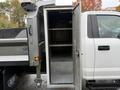 A 2021 Ford F-550 with a metallic storage compartment open on the side showing multiple shelves inside