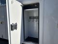 An open door of a 2013 International 7500 revealing an empty storage compartment with hooks inside