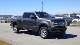 A 2017 Ford F-350 Super Duty truck in gray with chrome accents and a crew cab configuration parked in an open area