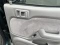 Door panel of a 2004 Toyota Tacoma featuring a gray fabric surface and a plastic handle