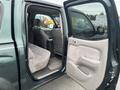 A 2004 Toyota Tacoma interior with an open passenger door revealing gray fabric seats and a clean floor mat
