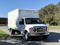 A white 2019 Ford E-450 box truck is parked with its front facing the viewer showcasing its large cargo area and shiny chrome grille