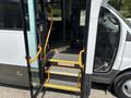 A 2020 Chevrolet Express bus with an open door revealing stairs and a warning sign to watch your step