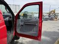 A red 2013 Ford F-550 with an open driver's door showing the interior handle and panel details