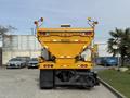 A 2016 International 7600 dump truck in bright yellow with rear lights and reflective markings, featuring dual compartments for material transportation