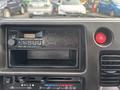 The dashboard of a 2010 Daihatsu Hijet featuring a radio unit with buttons and a speaker grille along with an air conditioning knob and hazard light button