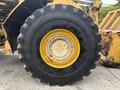 Close-up of a large tire from a 2012 Caterpillar 980 showcasing deep treads and a yellow rim with bolt holes