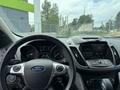 Interior view of a 2015 Ford Escape showcasing the steering wheel dashboard and center console with display screen and various control buttons