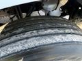 Close-up of a worn tire on a 2011 Freightliner M2 106 showing grooves and tread wear with some dirt accumulation on the surface