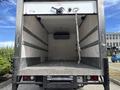 The interior of a 2018 Hino 195 truck with a cargo space featuring a flat wooden floor and silver metal walls with horizontal strips