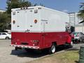 A red and white 2007 GMC C4500 TopKick truck with large rear doors and side compartments parked in a lot