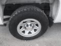 A close-up of a silver wheel and tire of a 2015 Chevrolet Silverado 1500 showing a rugged tread pattern and a Chevrolet logo on the wheel cover