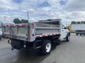 A 2011 Dodge Ram 5500 dump truck with a gray bed and white cab parked on a pavement surface