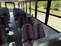 Interior view of a 2011 Freightliner B2 school bus featuring rows of gray seats with red stripes and an empty aisle running through the center