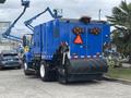 A blue 2013 International DuraStar 4300 street sweeper with a large broom at the front and multiple lights on the rear