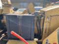 A yellow 2010 Vermeer Corporation BC1200XL wood chipper with a dark cover and a red tube in the foreground