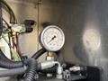 Close-up of a pressure gauge displaying readings between 0 to 500 PSI connected to a series of hoses and fittings in an industrial setting