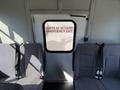 Interior of a 2021 Ford Econoline showing gray seats and an emergency exit door with signage in English and French
