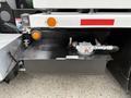A black fuel tank mounted below a 2016 Peterbilt 348 truck with visible fittings and a gauge on top