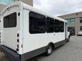 A white 2017 Chevrolet Express van with large tinted windows and a gray lower section parked next to a building