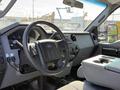 Interior of a 2015 Ford F-550 featuring a steering wheel a dashboard with controls and a center console with storage
