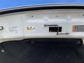 Close-up of the underside of a 2018 Ford F-150 hood featuring warning labels and a latch mechanism