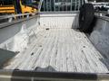 2014 Ford F-250 SD truck bed with a worn, textured surface and a spare tire leaning against the side