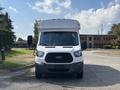 A white 2018 Ford Transit-350 van is facing directly towards the camera showcasing its front grille headlights and windshield