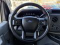 A steering wheel of a 2021 Ford Econoline with Ford logo and control buttons on the spokes