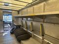 A 2012 Ford E-450 interior with metal shelves and several tires stacked beside them