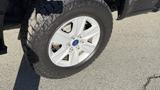 A close-up of a white alloy wheel with a five-spoke design mounted on a rugged tire showing tread pattern on a 2016 Ford F-150