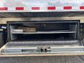 The image shows the open storage compartment of a 2022 Freightliner M2 106 revealing metal shelving and tools inside